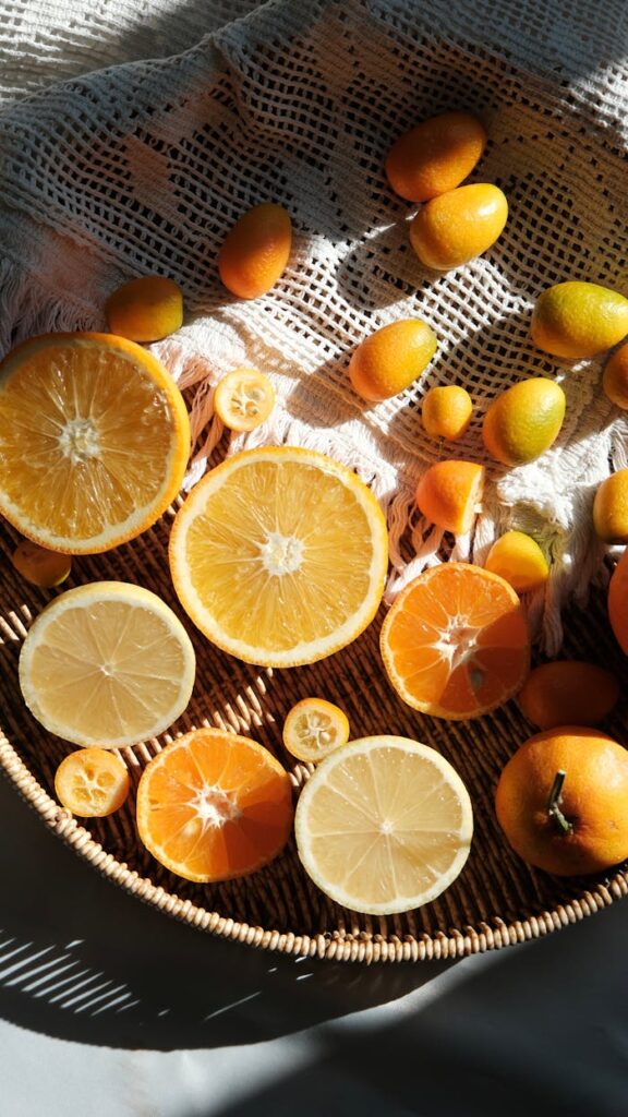 A variety of sliced citrus fruits on a woven tray, beautifully lit by sunlight, showcasing fresh colors and textures.